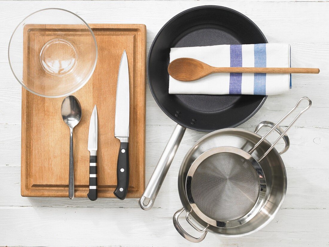 Various kitchen utensils: pan, pot, strainer, glass bowl, knives, spoon