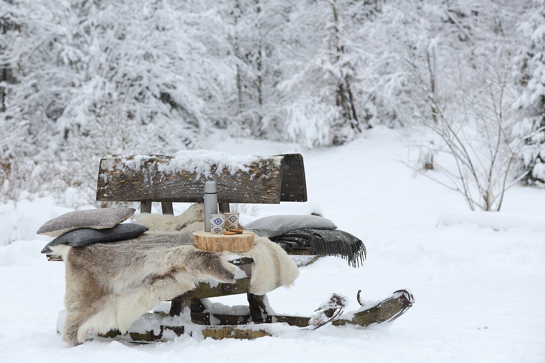 Alter Hornschlitten als Bank im verschneiten Garten