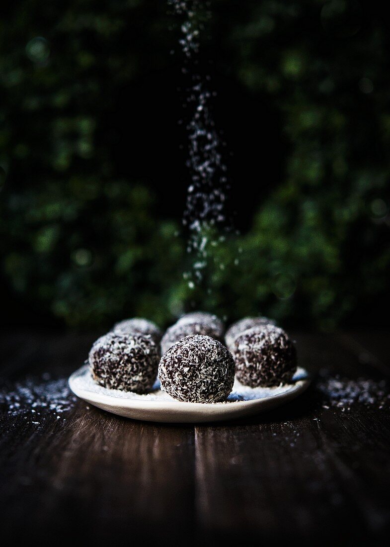 A plate of spiced chocolate brownie rum balls rolled in coconut flakes