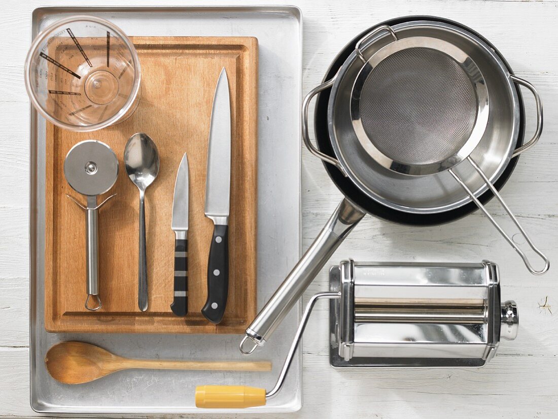 Various kitchen utensils: pasta machine, pot, pan, sieve, measuring cup