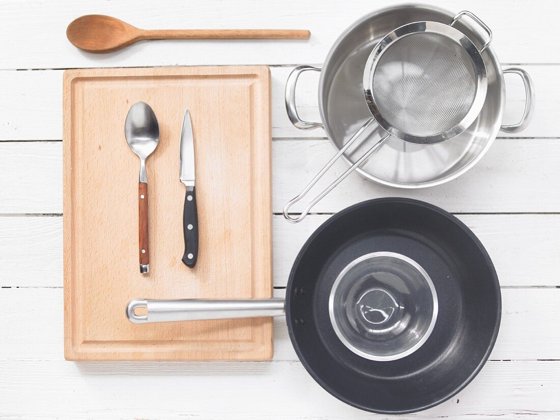 Various kitchen utensils: pot, strainer, pan, spoon, knife
