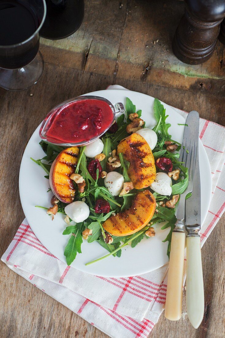 Salad with grilled peaches, mozzarella, walnuts, cherries and cherry dressing