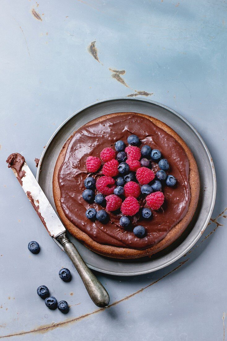 Chocolate cake with fresh berries and chocolate cream, served with vintage knife