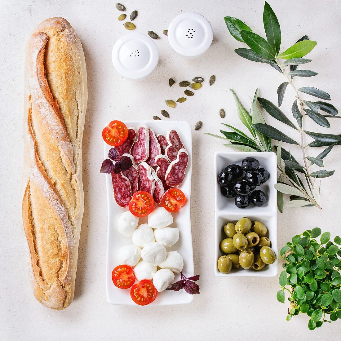 Antipasti: Baguette, Salami, Mozzarella, Tomaten und Oliven (Aufsicht)