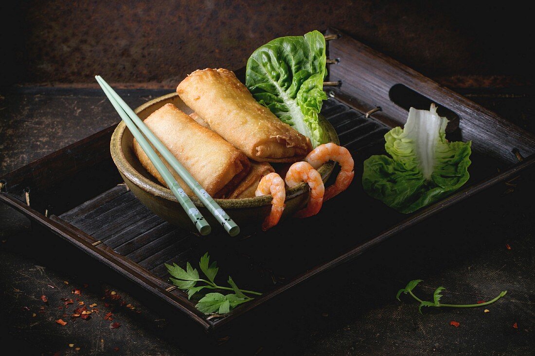 Fried spring rolls with vegetables and shrimps, served in ceramic bowl with chopsticks