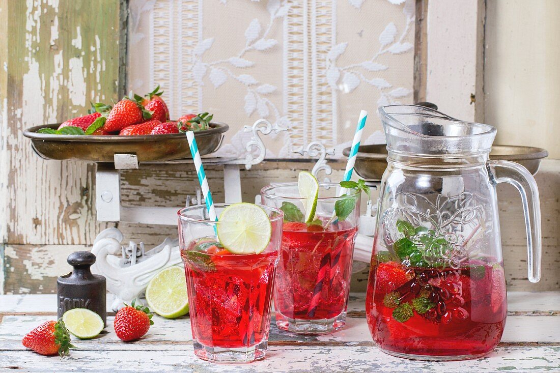 Selbstgemachte Erdbeerlimonade serviert mit Minze und Limetten in Gläsern und Krug