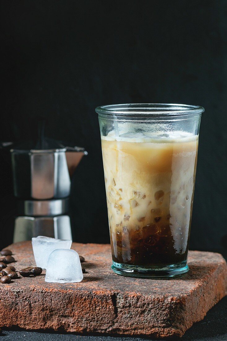 Ein Glas Eiskaffee mit Milch und Sahne serviert auf Steinplatte