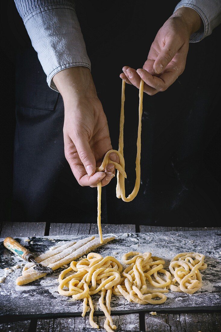 Person formt Pasta Pici (handgerollte Spaghetti, Toskana, Italien)