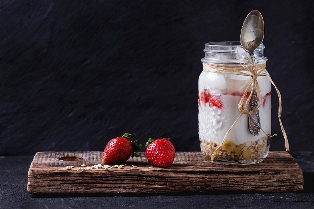 Müsli mit Joghurt und Erdbeeren, serviert mit Löffel in Schraubglas