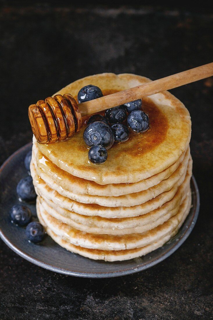 Ein Stapel Pancakes mit Honig und Heidelbeeren