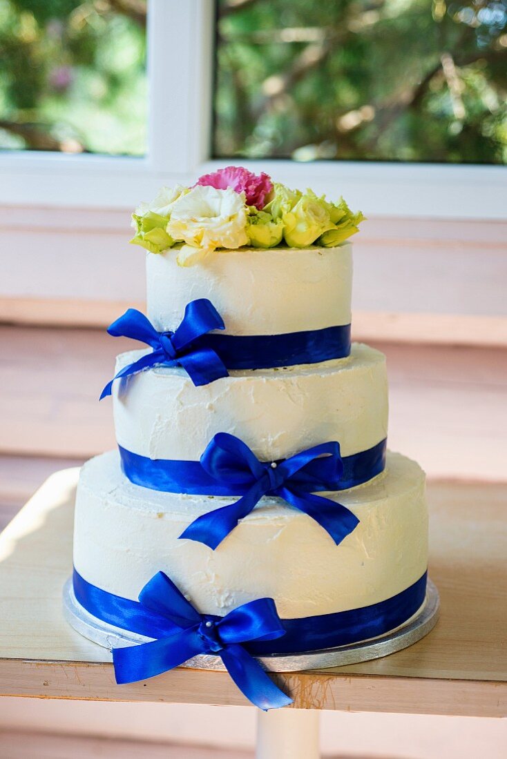 A three-tiered buttercream wedding cake with blue silk ribbons