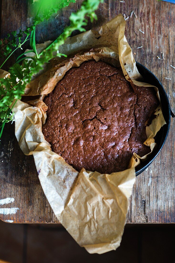 A freshly baked chocolate cake on baking paper in a tin