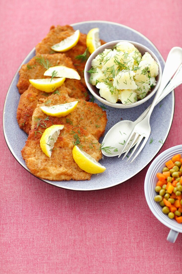 Pork schnitzels with potatoes, carrots and peas