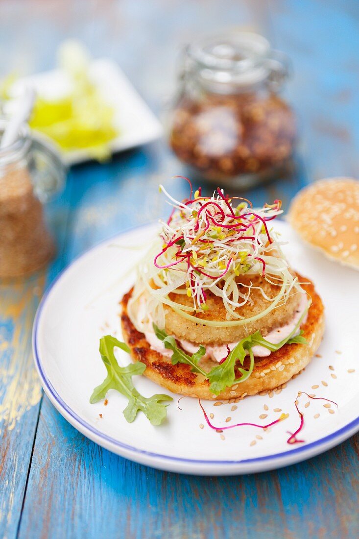 A fish burger with pink sauce and bean sprouts