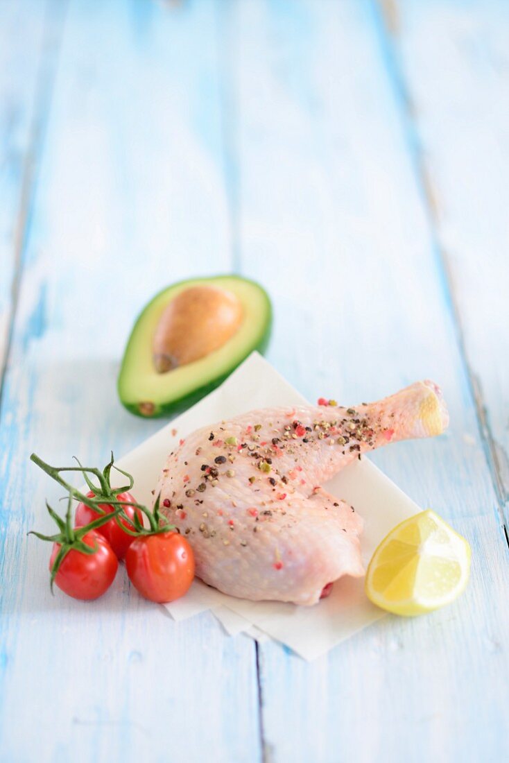 A spiced chicken leg with cherry tomatoes, lemon and avocado