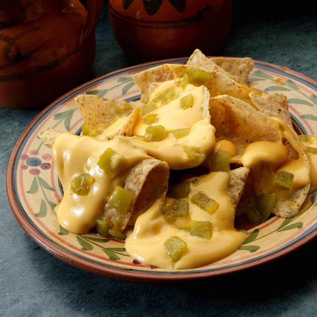 White corn tortilla chips with cheese sauce and chopped green peppers