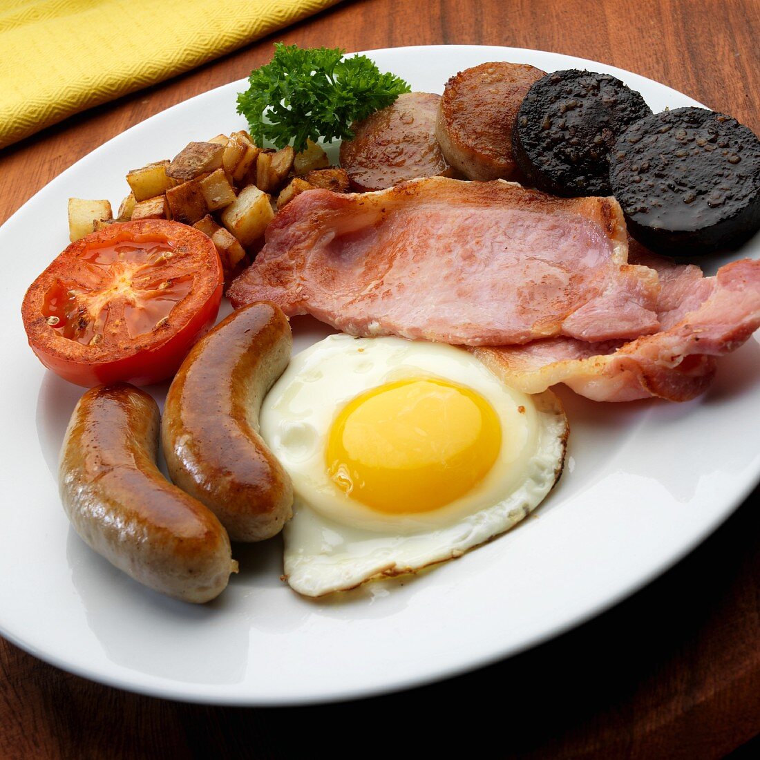 Full English, Irish breakfast with egg, bacon, bangers, black pudding, white pudding fried potatoes, tomato