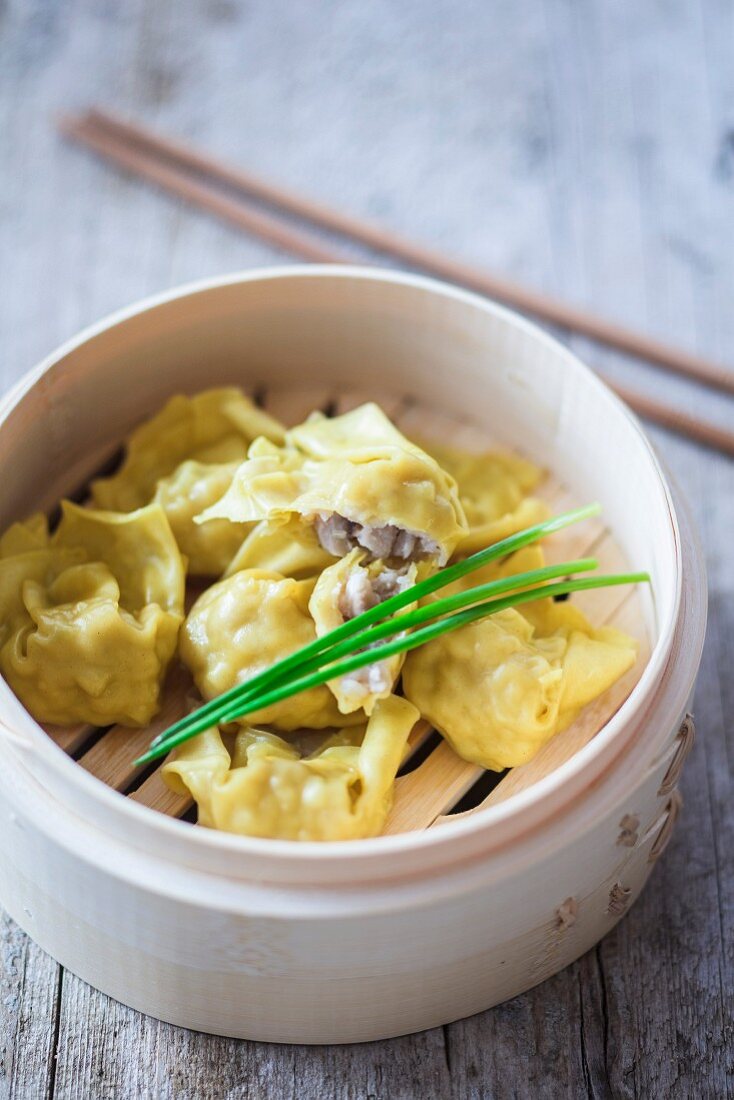 Won tons with chives in a bamboo steamer