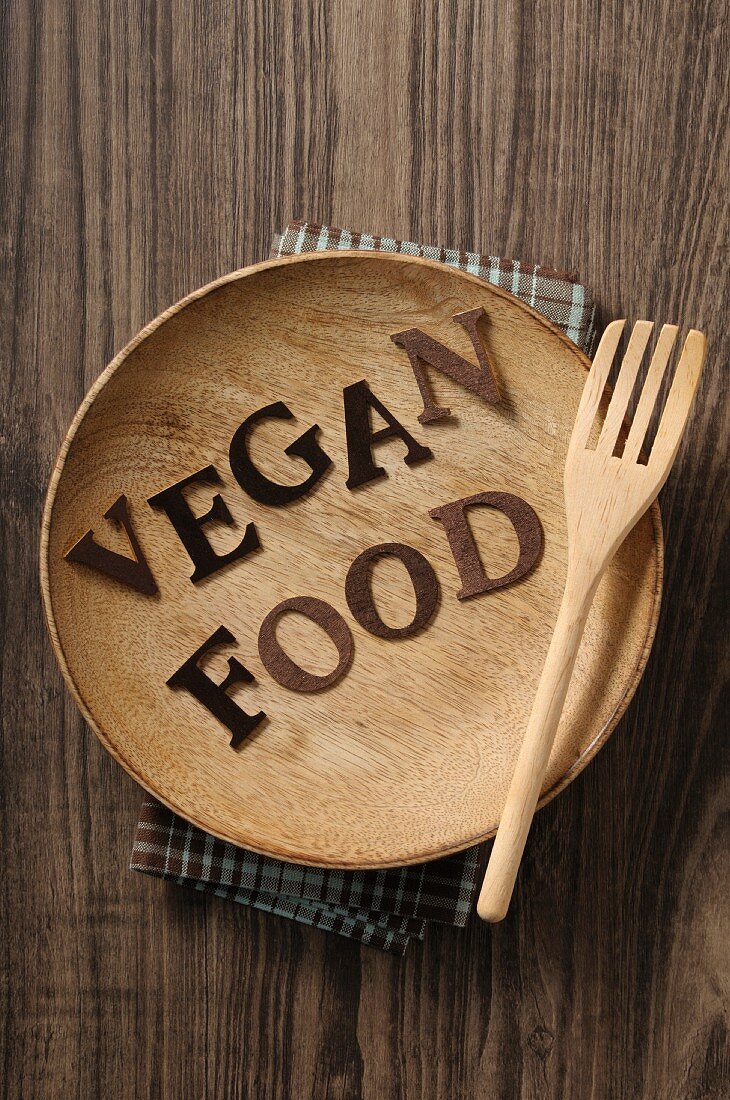 Schrift Vegan Food auf Holzteller mit Gabel