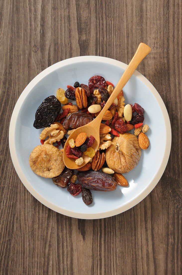 Dried fruit and nuts in a bowl with a wooden spoon