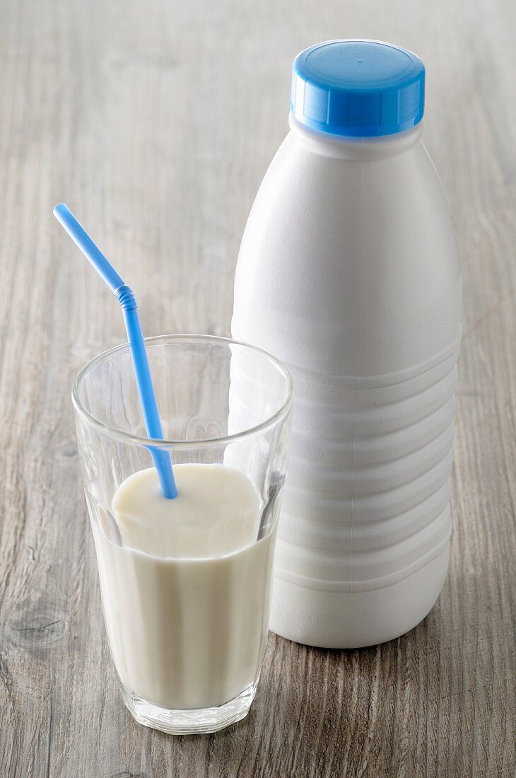 A glass of milk with a straw and a milk bottle