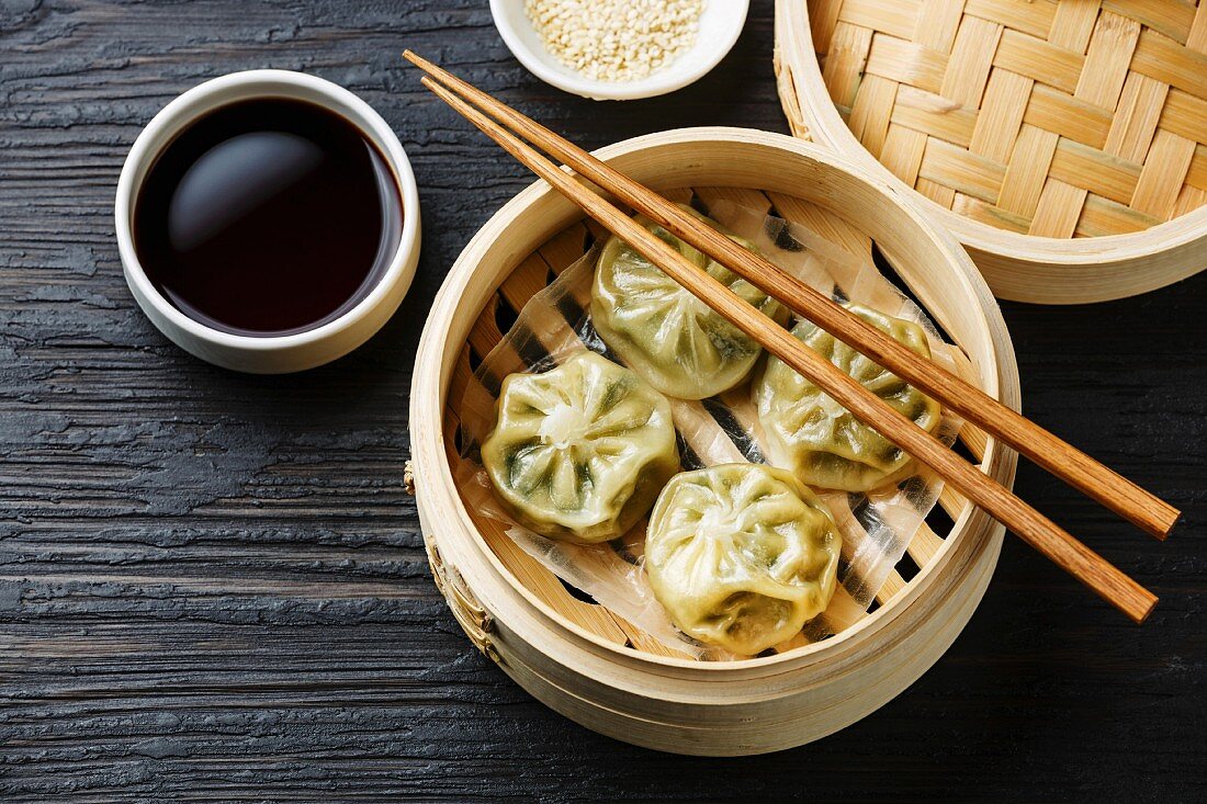 Steamed dumplings Dim Sum in bamboo steamer on black burned wooden background