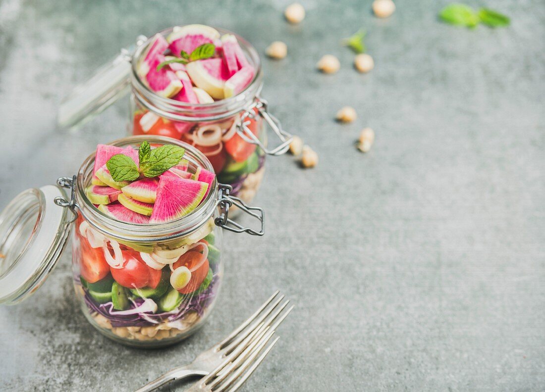 Vegetable and chickpea sprout layered vegan salad in glass jars