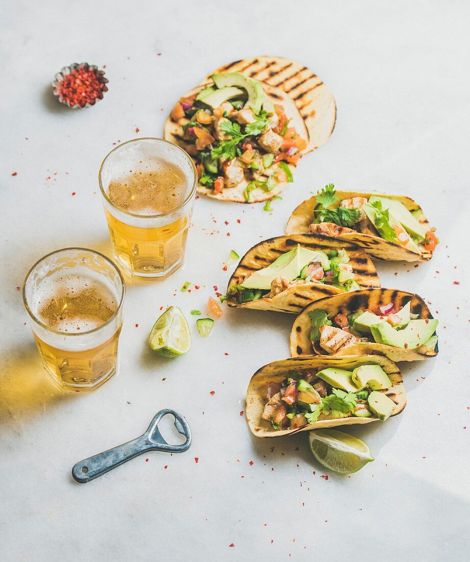 Tacos mit gegrilltem Hähnchenfilet, Avocado und Salsa, dazu Bier in Gläsern