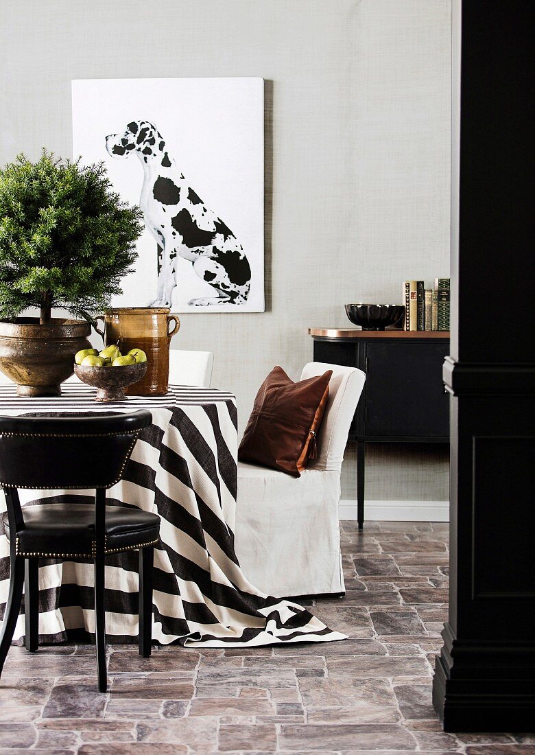 Nadelbäumchen auf Tisch mit schwarz-weisser Tischdecke, Stühle, schwarzer Sideboard und Bild mit Dalmatiner-Motiv an der Wand