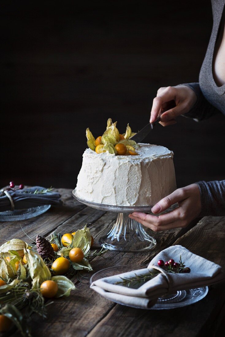 Frau schneidet Chiffon-Cake mit Physalis an