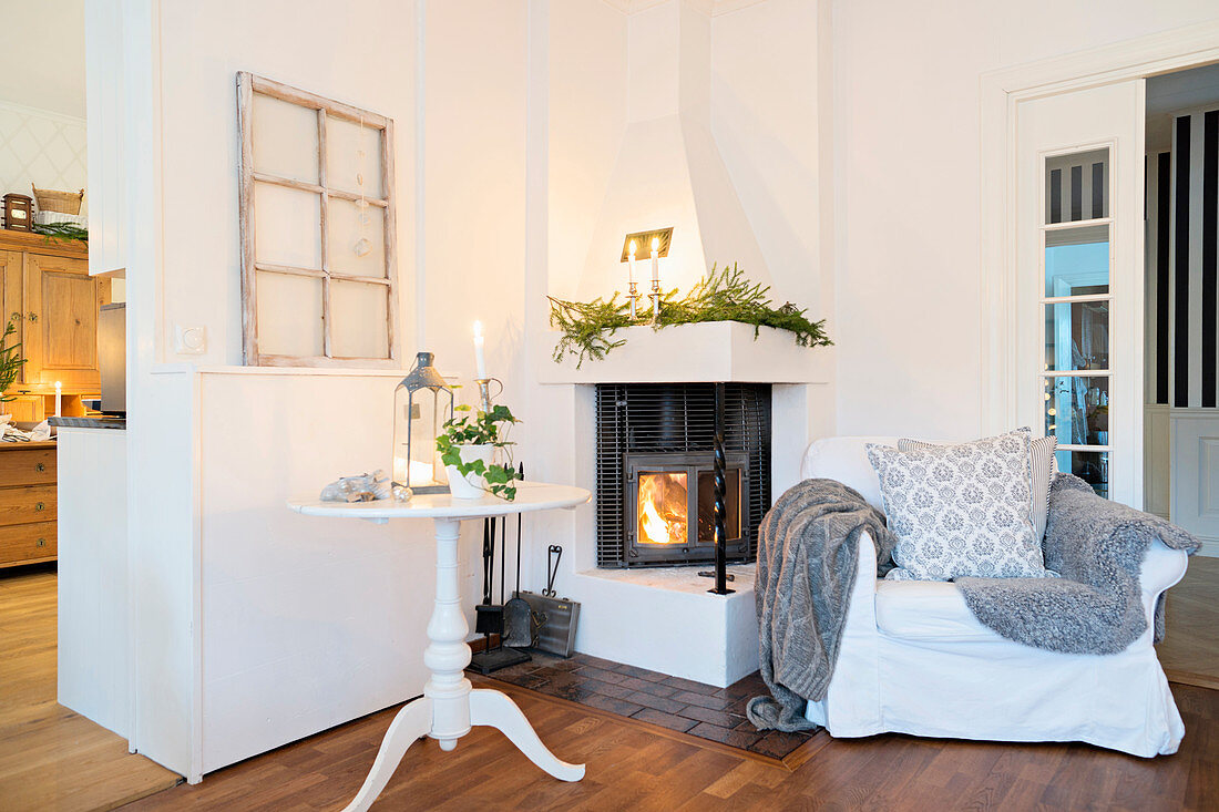 Comfortable armchair and side table in front of lit fire