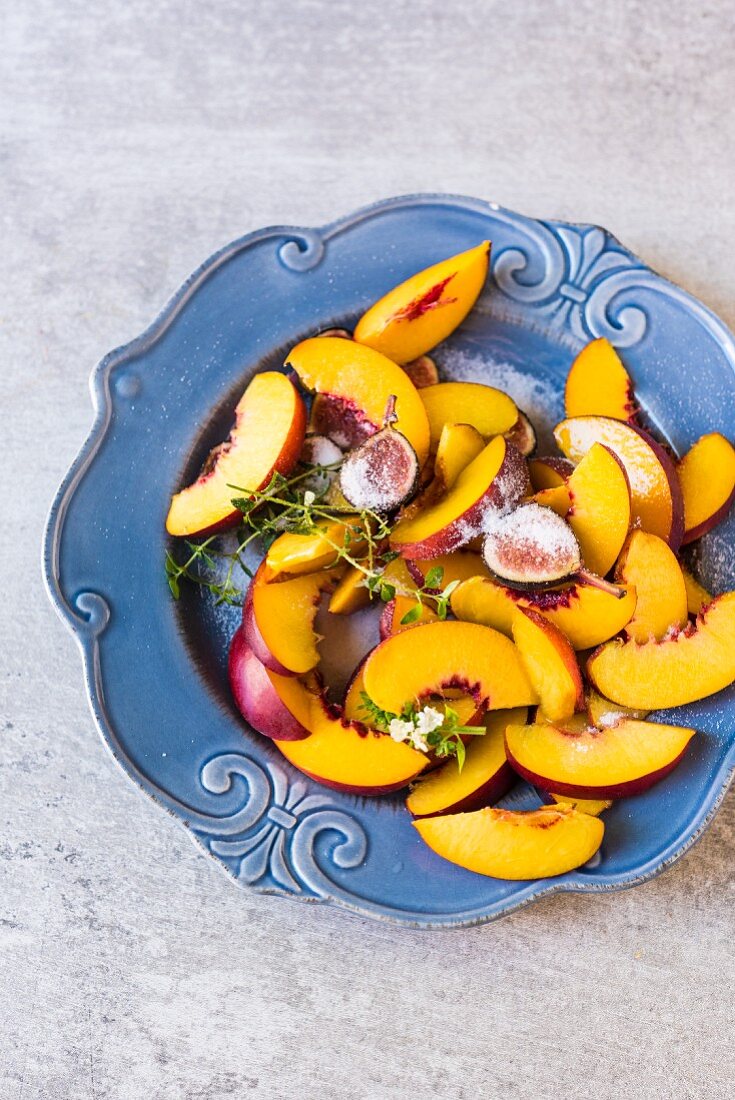 Nectarine slices and figs with sugar on a plate