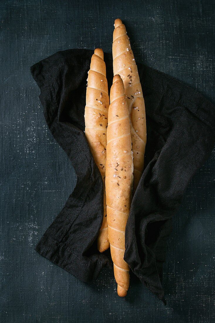 Three twisted breads with salt and cumin on black textile