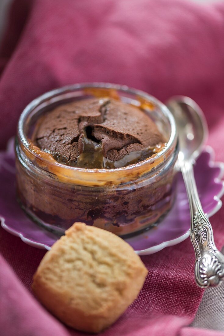 Baked chocolate pudding with salted caramel sauce in a glass ramekin