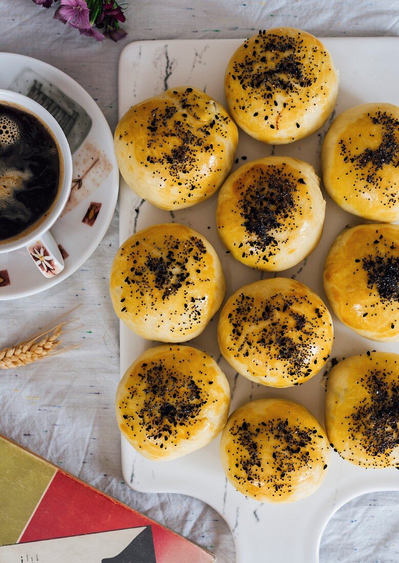 Turkish buns stuffed with feta and parsley served on a board and accompanied by a cup of coffee