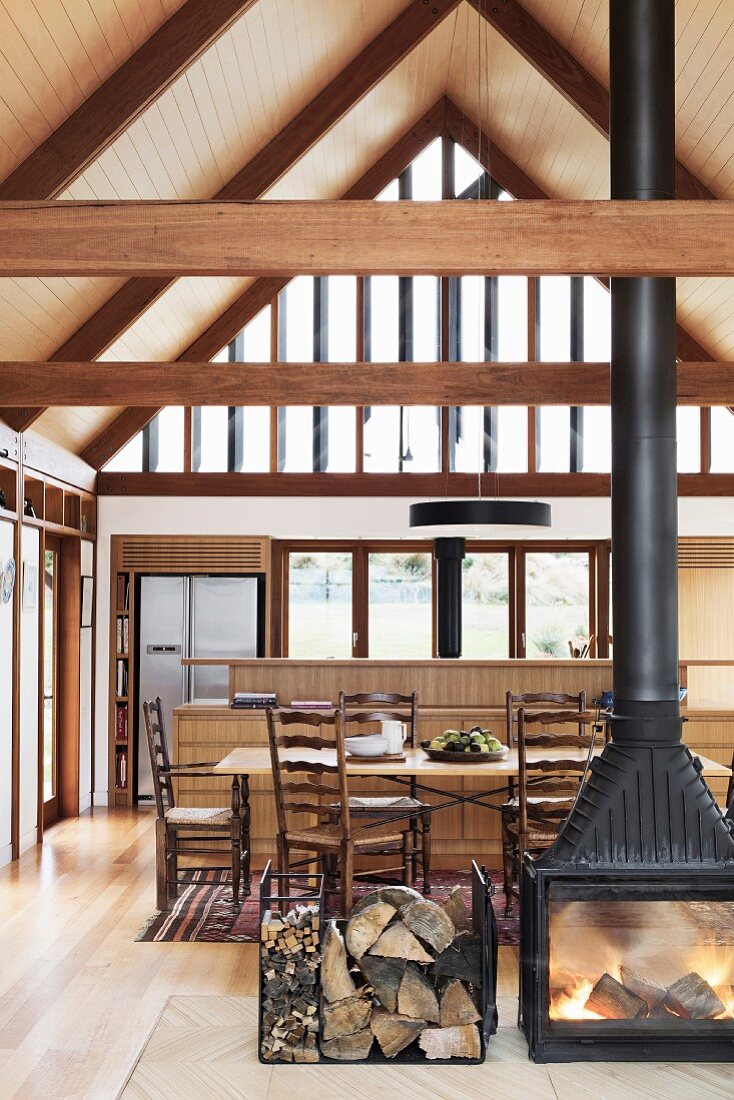 Black wood-burning stove in an open living room with visible roof beams and gable glazing