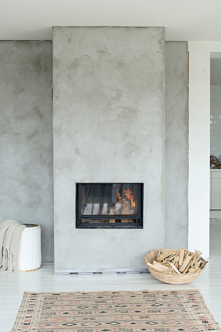 Basket of firewood next to fireplace in concrete wall