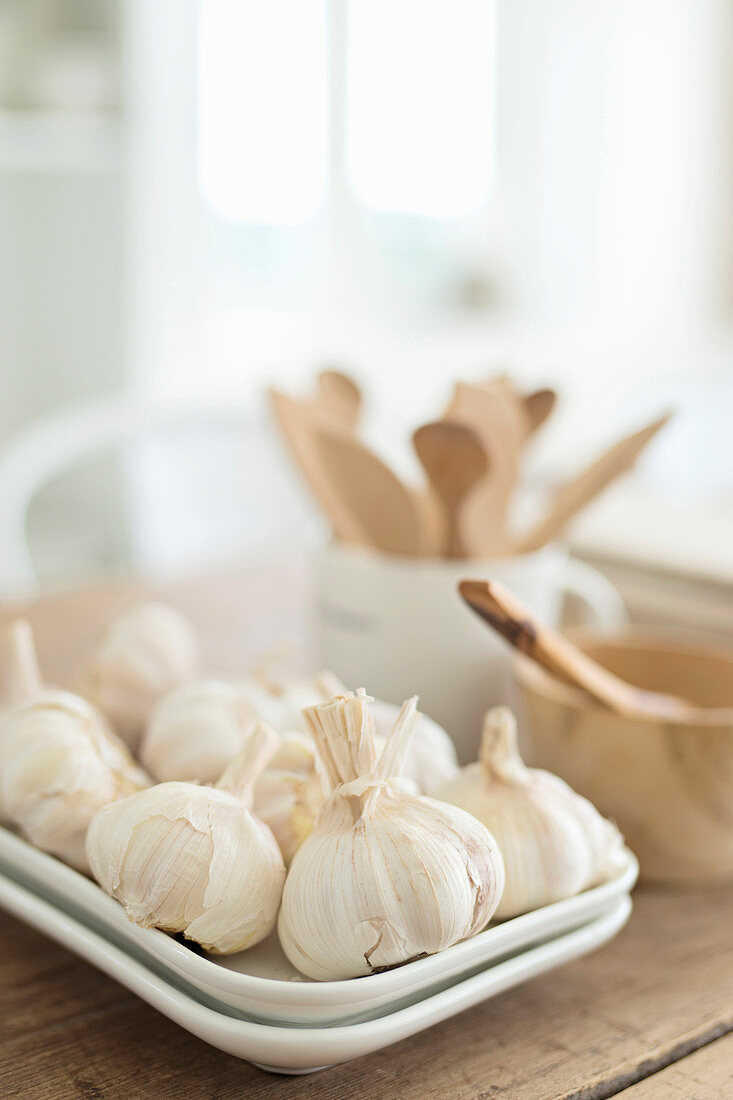 Bulbs of garlic on rectangular plates against blurred background