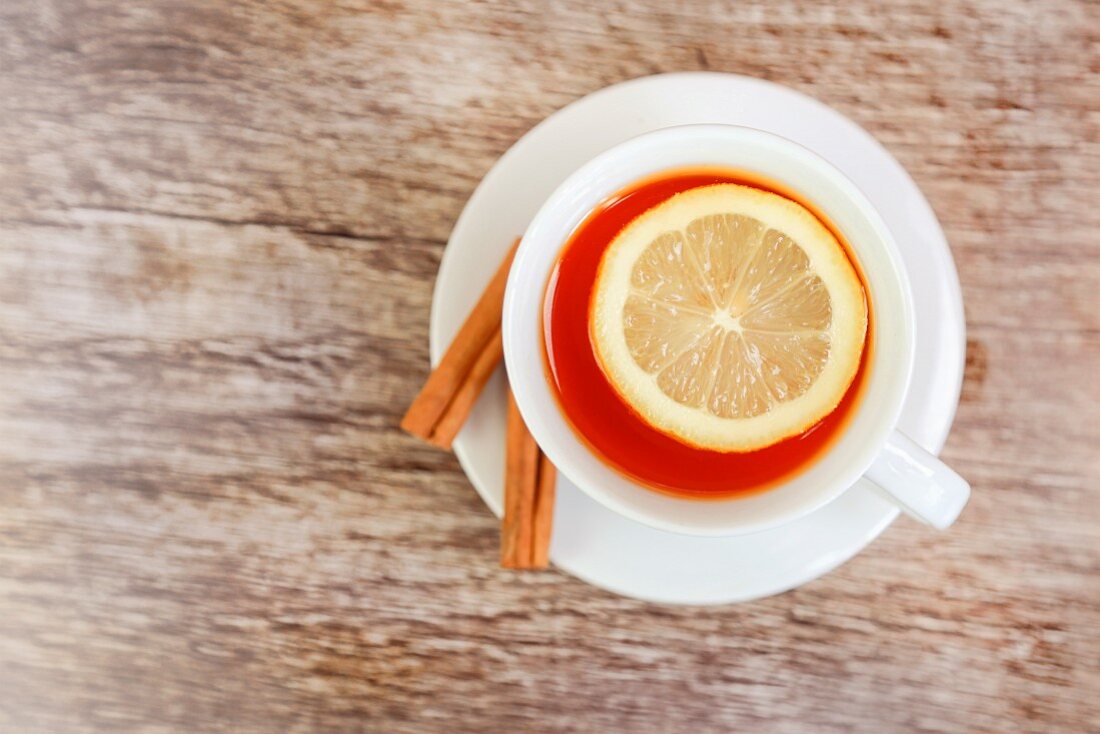 Eine Tasse Tee mit Zitrone und Zimtstangen