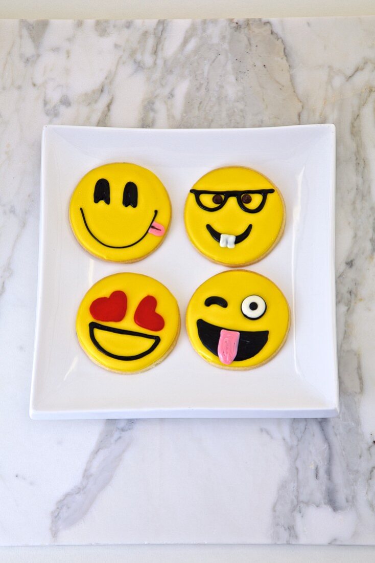 Four cookies decorated with funny smiley faces