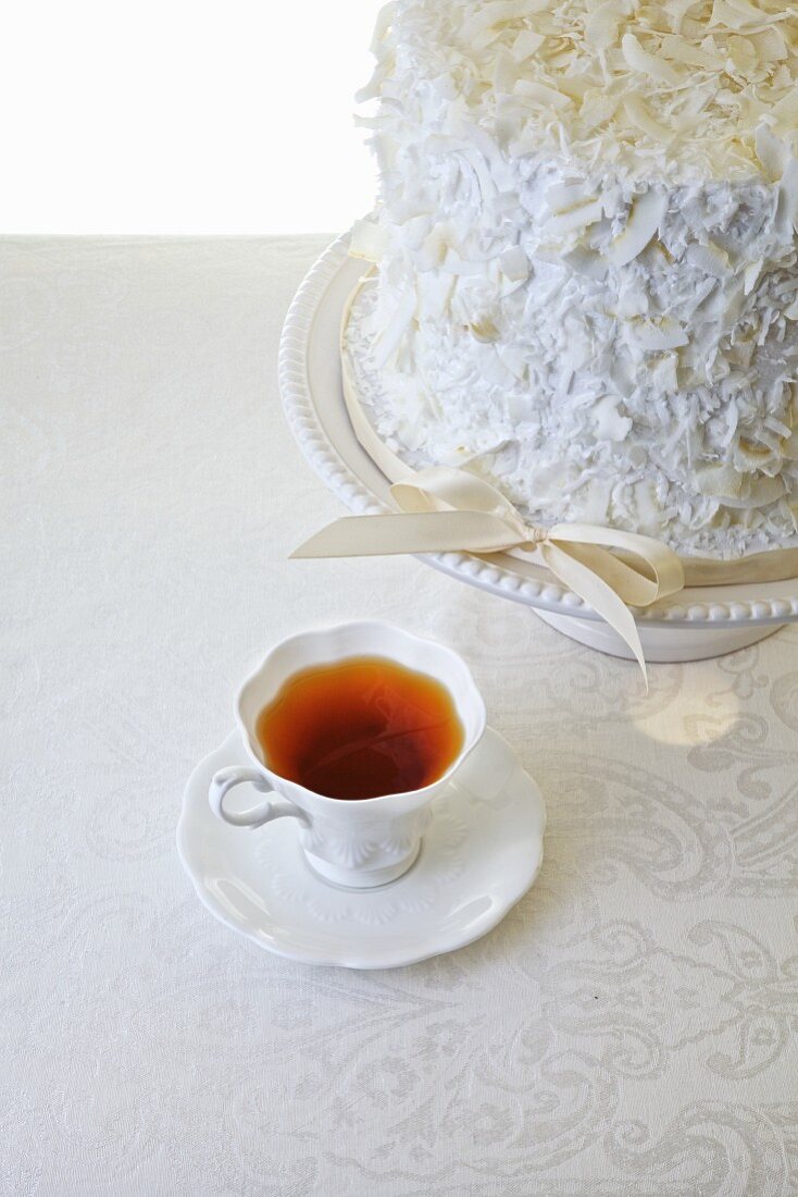 weiße Schokoladen-Vanilletorte mit Tasse Tee auf weißem Untergrund