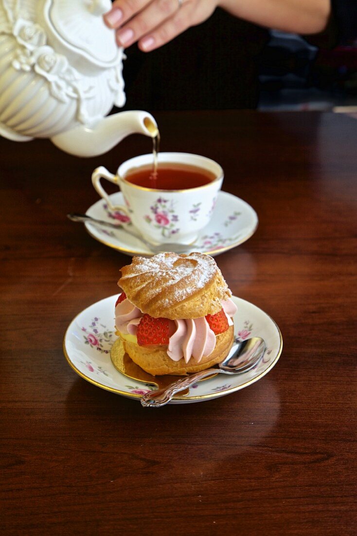 Cream puff pastry with strawberries being served with tea