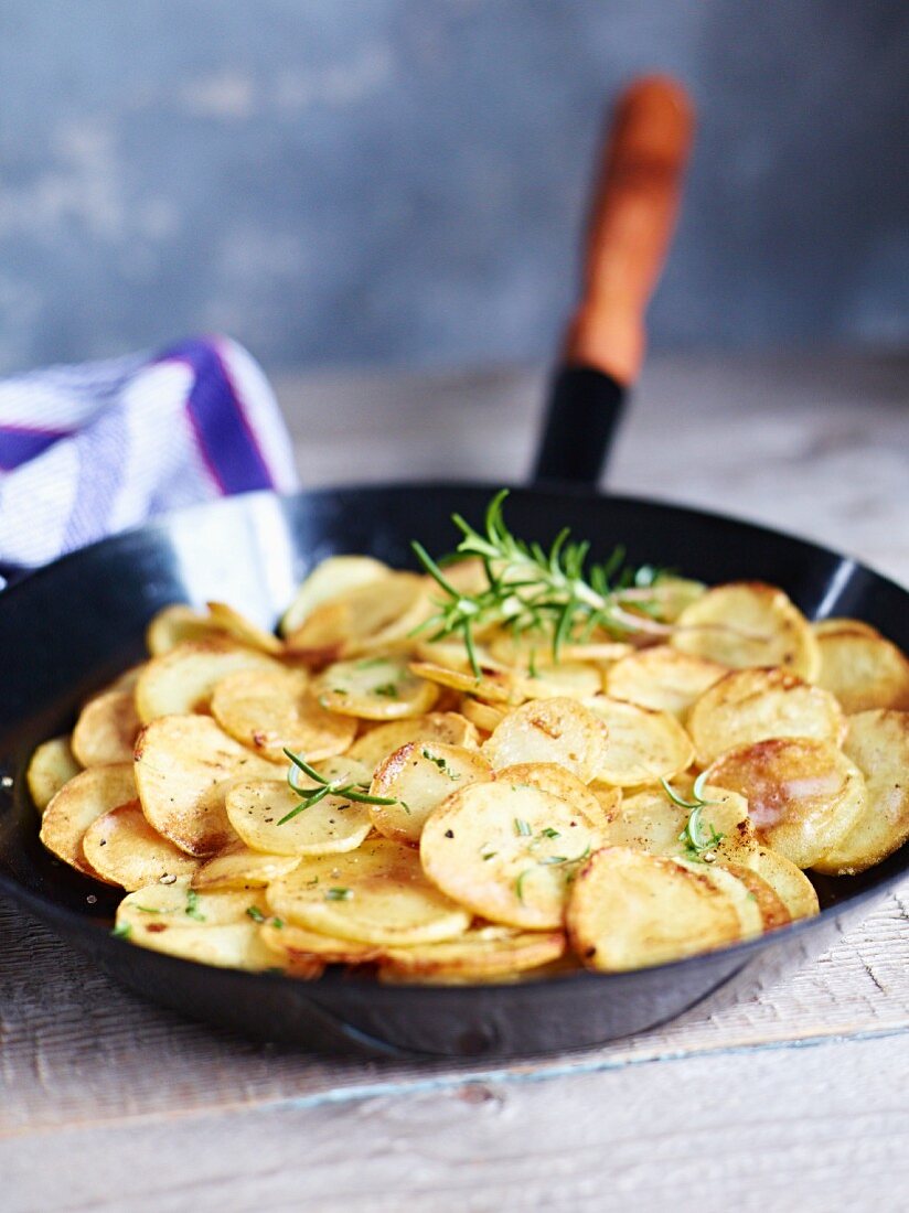 Fried potatoes with rosemary in a pan