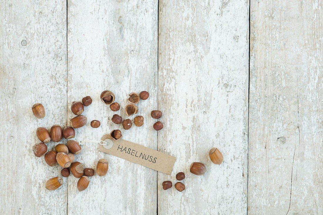 Hazelnuts with a brown paper label on a wooden background (top view)