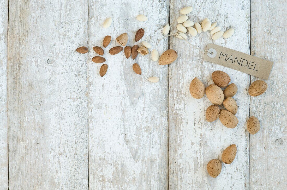 Almonds with a brown paper label on a wooden background (top view)