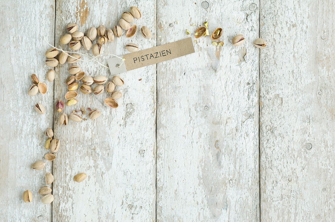 Pistachios with a brown paper label on a wooden background (top view)