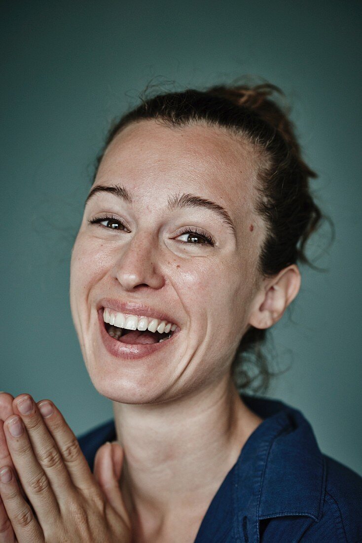 A brunette woman with her hair in a bun, wearing a blue shirt