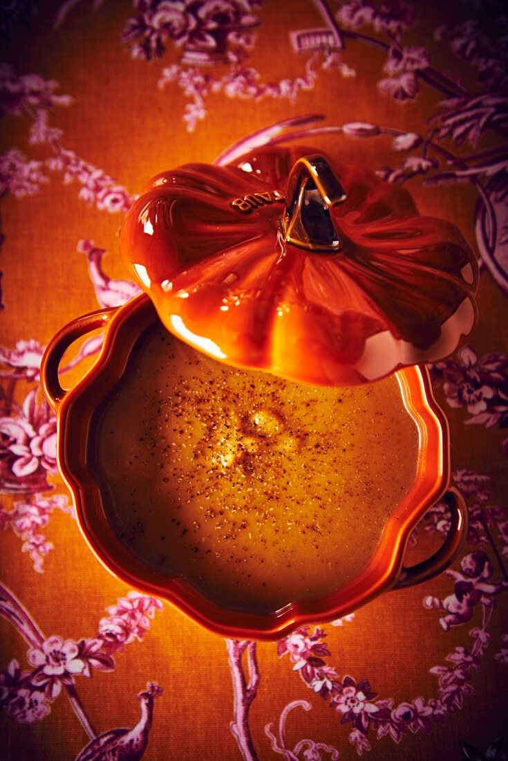 Butternusskürbissuppe mit Kastanien in orangefarbener Suppenterrine (Aufsicht)