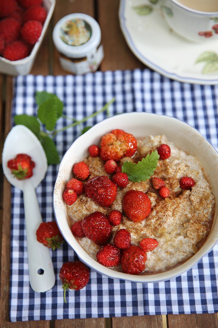 Summer breakfast porridge with strawberries on a garden table