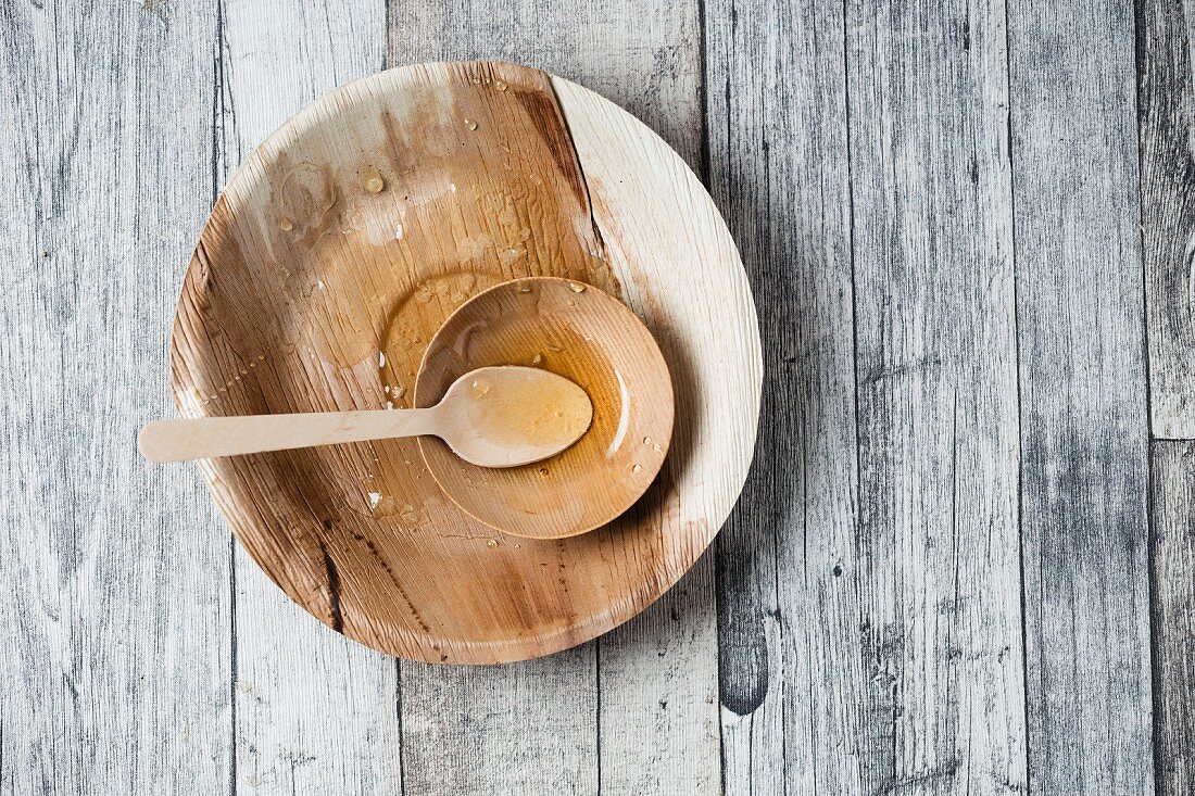 Remains of honey on a wooden plate with a spoon